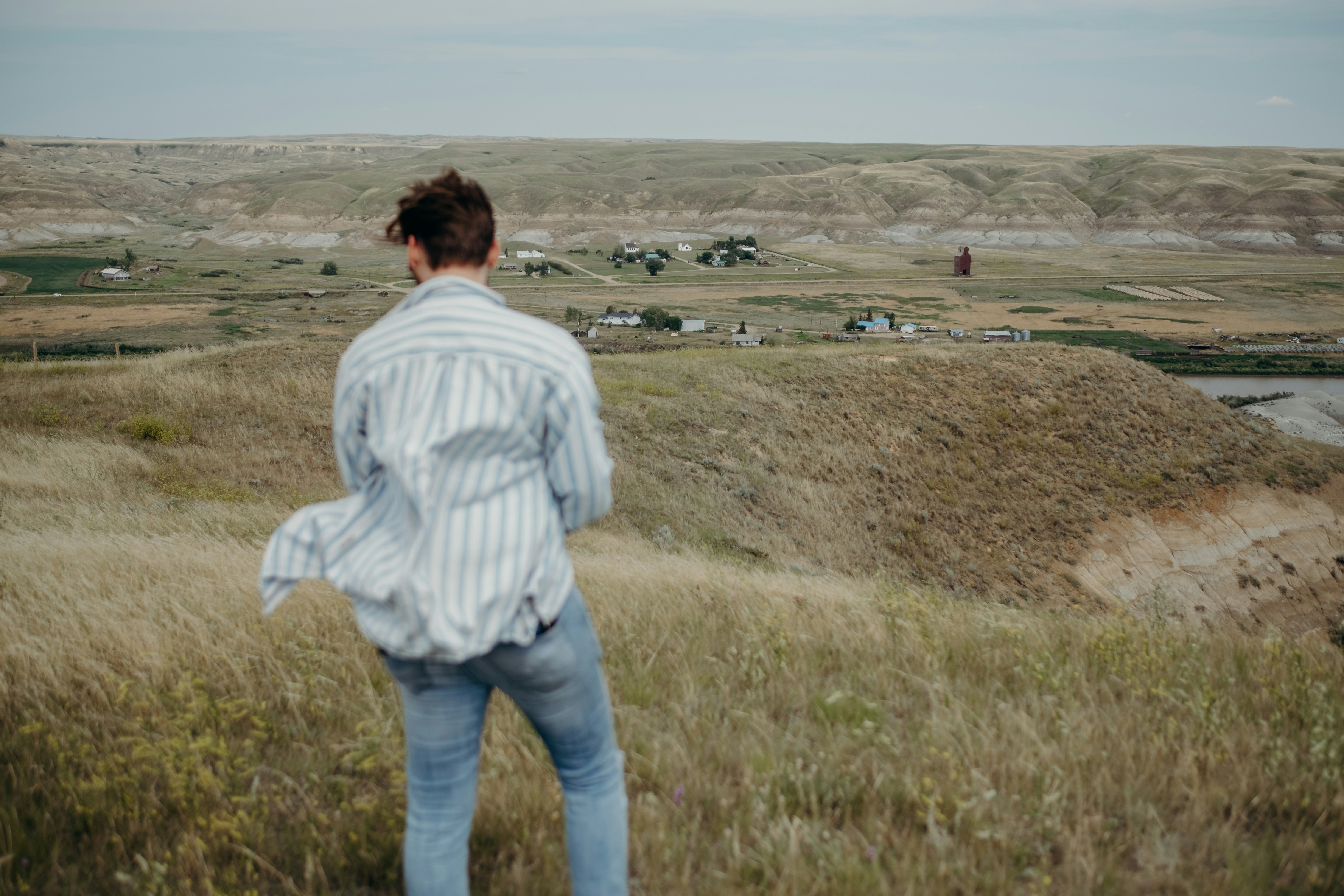 woman in white and gray striped long sleeve shirt and blue denim jeans standing on brown